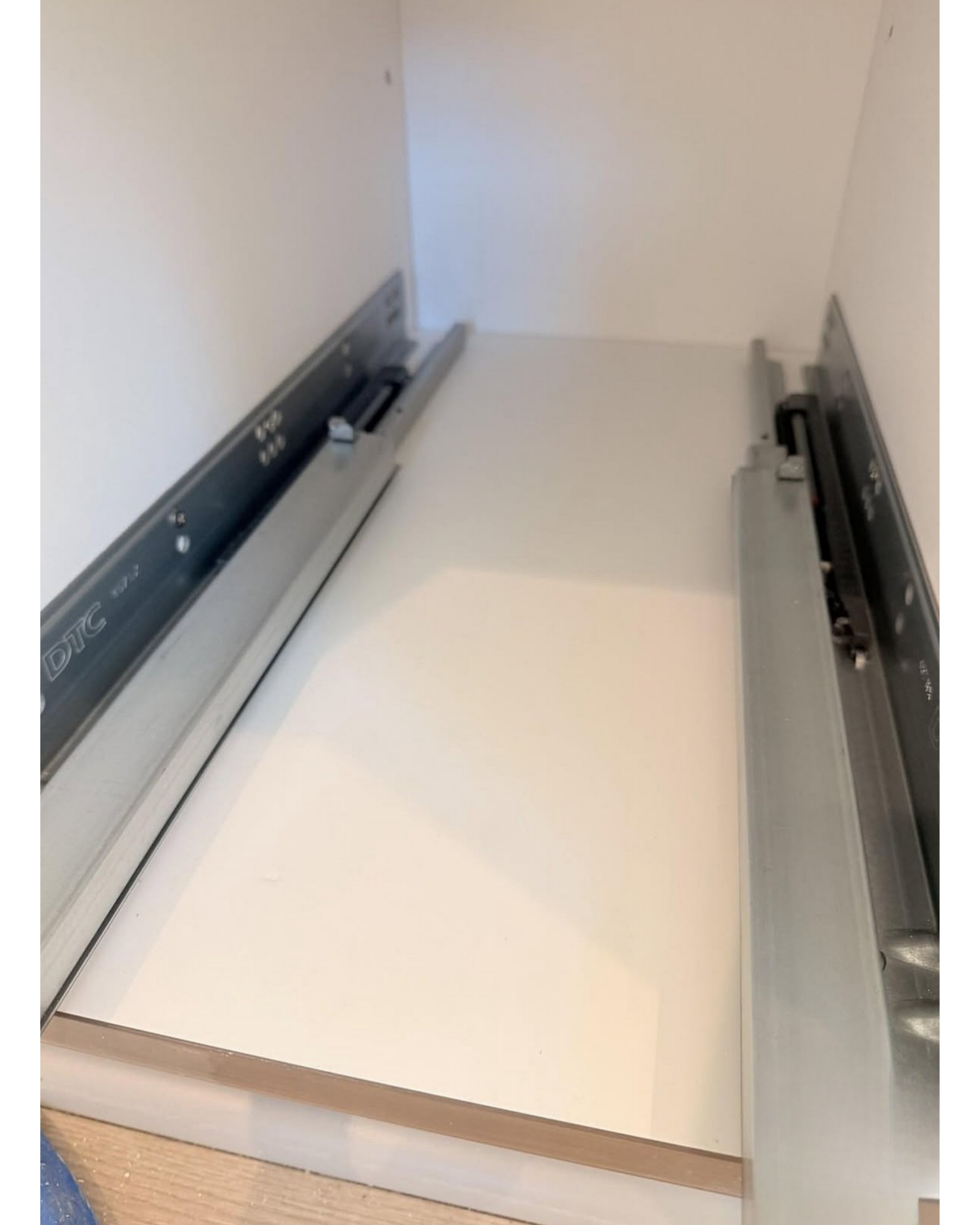 White cabinet drawer with metal slides extended inside an empty cabinet frame