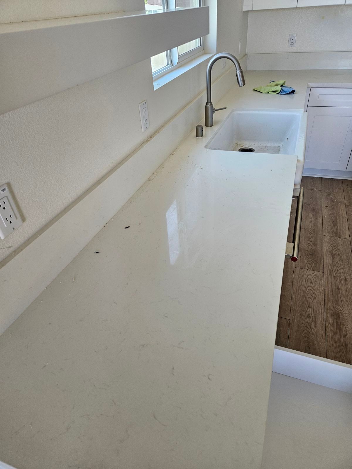 Bright white kitchen countertop with sink, faucet, and wood flooring