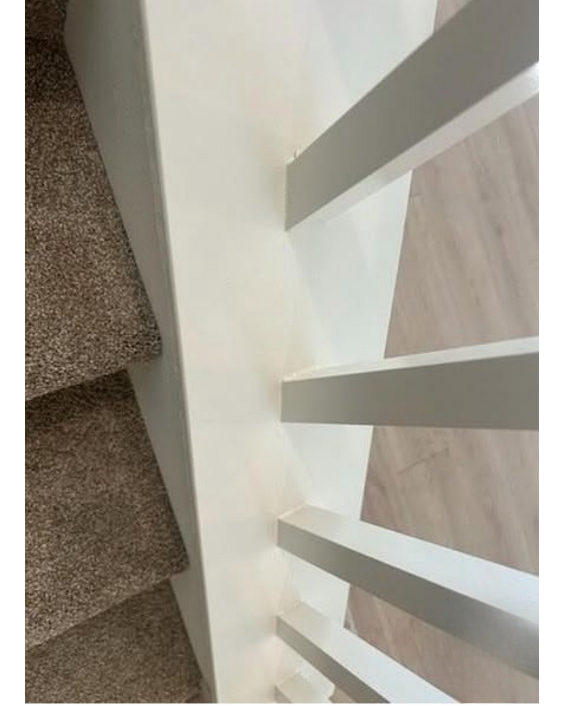 Indoor staircase with white railings and brown carpeted steps viewed from above