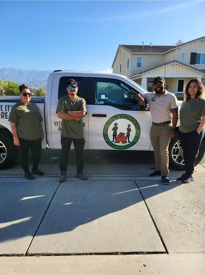 Four people standing by a white pickup truck with a city seal in a sunny driveway.