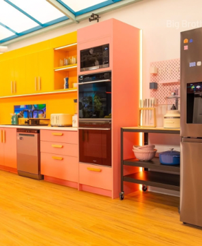 Colorful modern kitchen with yellow cabinets, pink oven tower, wood floor, and stainless steel appliances