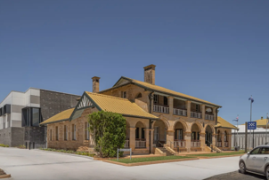 Historic brick building with arched porches and yellow roof on a sunny street corner