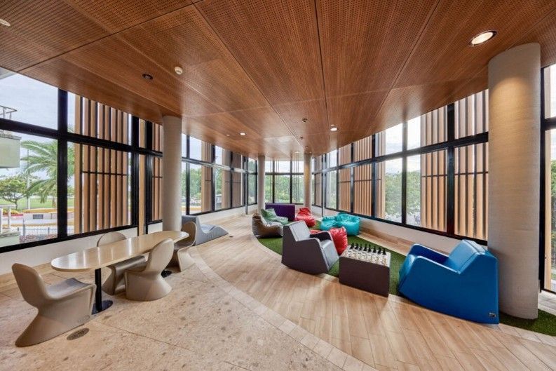 Modern lounge with wood ceiling, large windows, and colorful modular seating.
