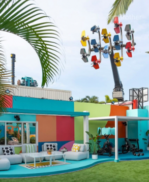 Colorful beachfront café with outdoor seating and a tall pole of spinning ride chairs under palm trees