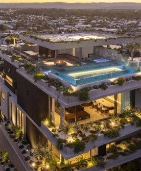 Modern rooftop luxury villa with illuminated pool at dusk, surrounded by greenery and cityscape