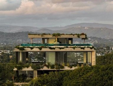 Modern villa with green rooftop terraces on a hillside, overlooking a hazy mountain valley
