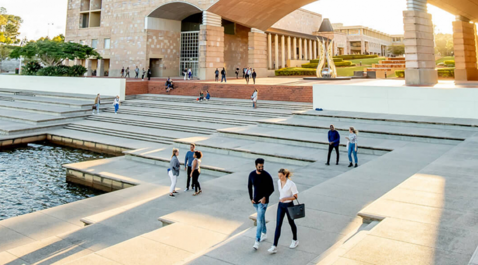 Three construction workers in hard hats inspect a modern building courtyard.