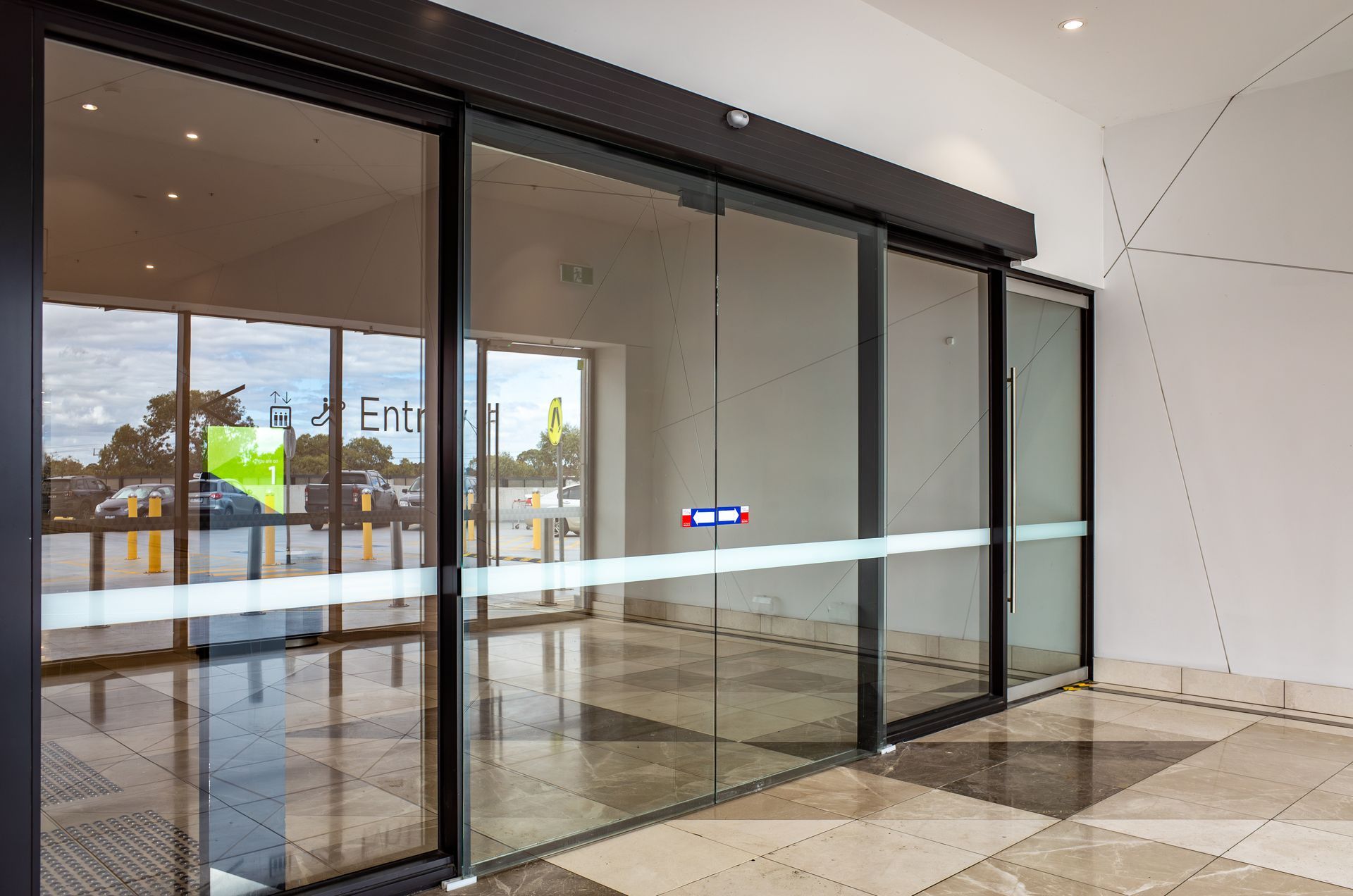 Empty glass automatic sliding doors in a bright modern lobby entrance. Empty glass automatic sliding doors in a bright modern lobby entrance.