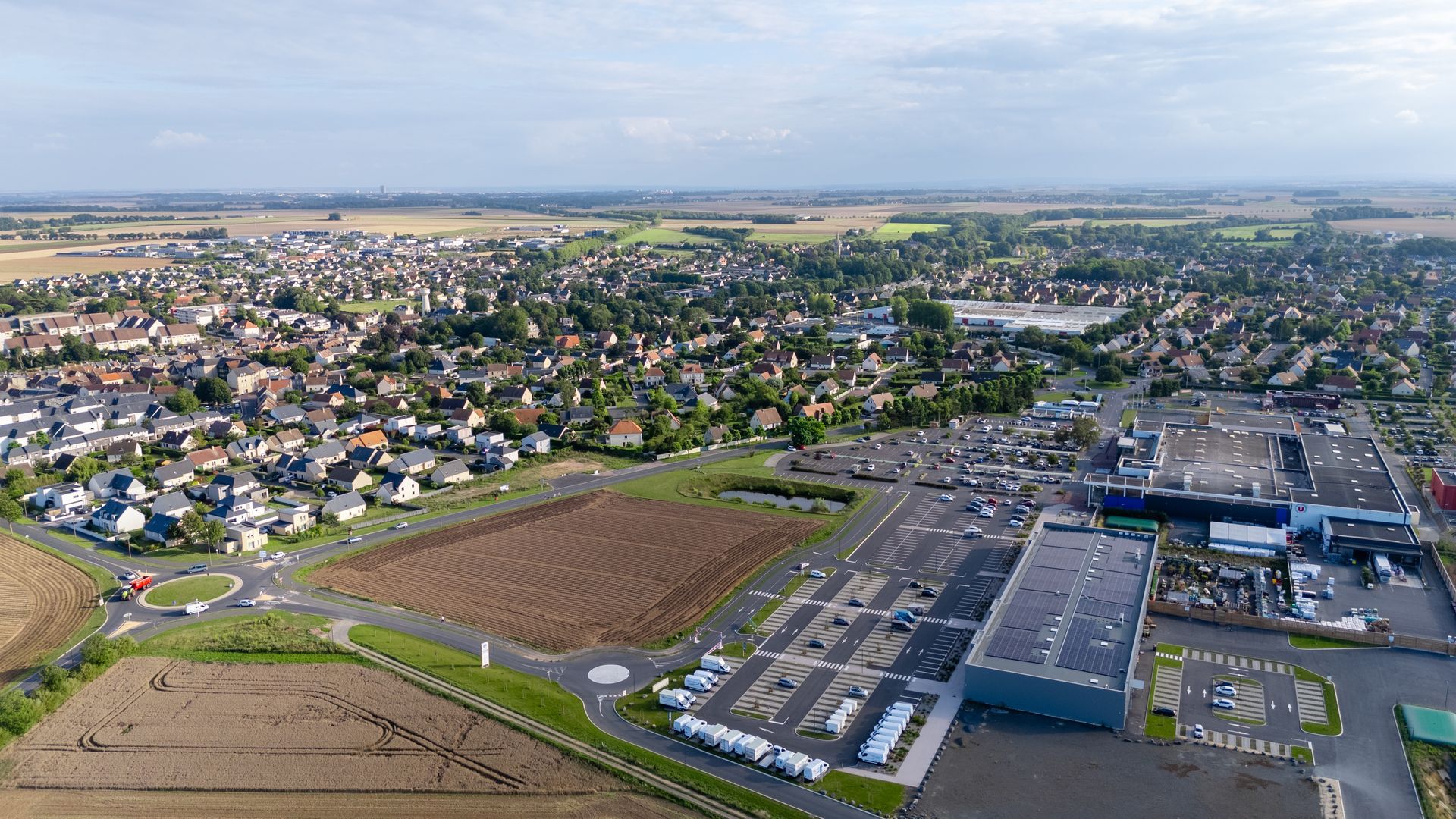 Aerial view of a suburban neighborhood, fields, and a large industrial warehouse complex. Aerial view of a suburban neighborhood, fields, and a large industrial warehouse complex.