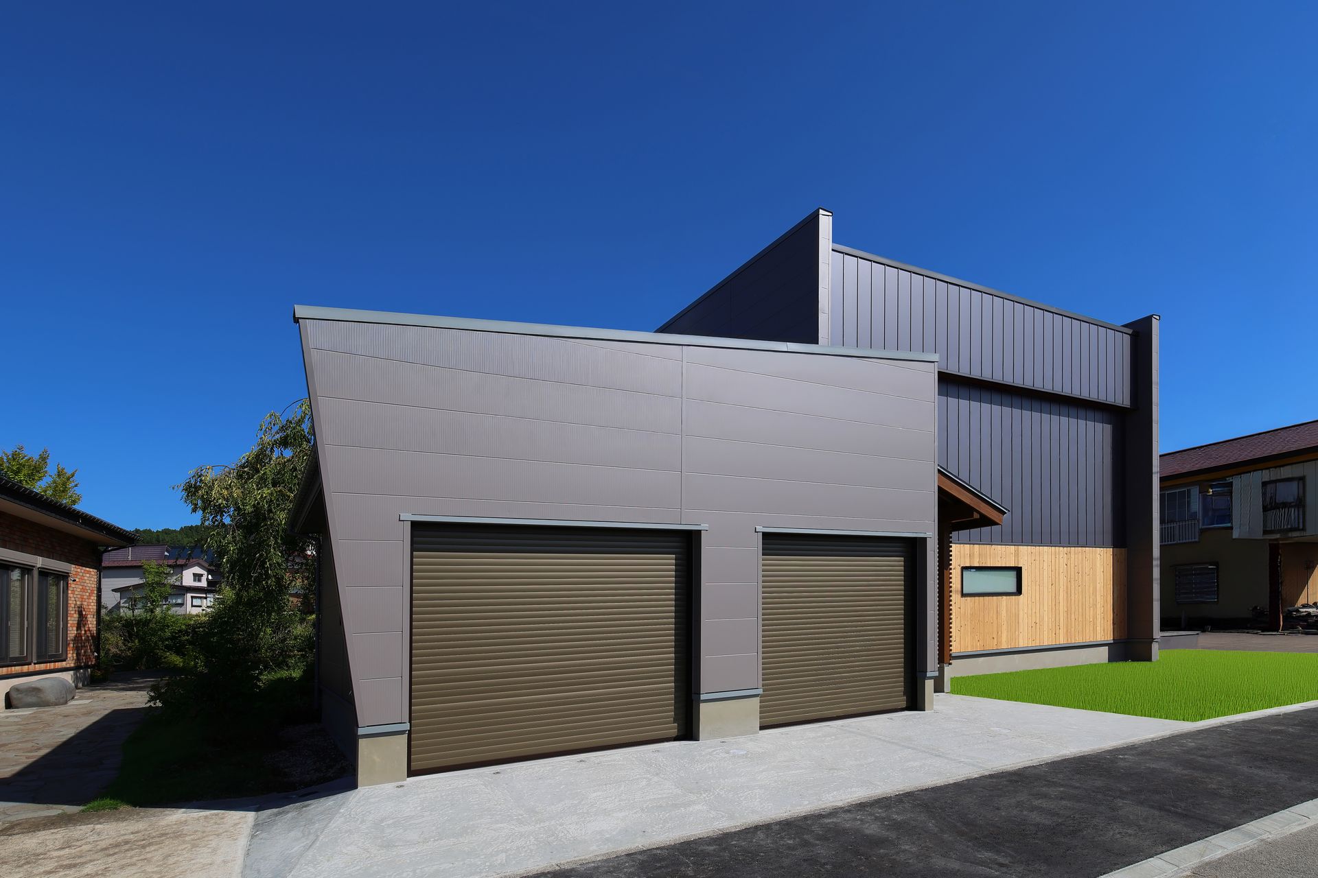 Modern gray house exterior with two garage doors under a clear blue sky Modern gray house exterior with two garage doors under a clear blue sky