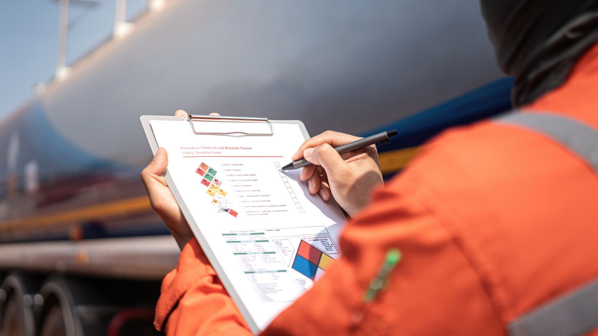 Person in orange safety vest writing on a clipboard beside a train