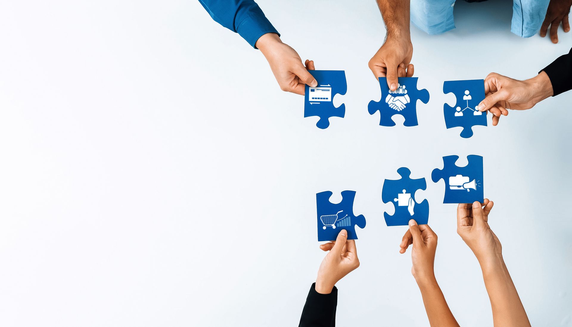 Hands assembling blue puzzle pieces together on a white background