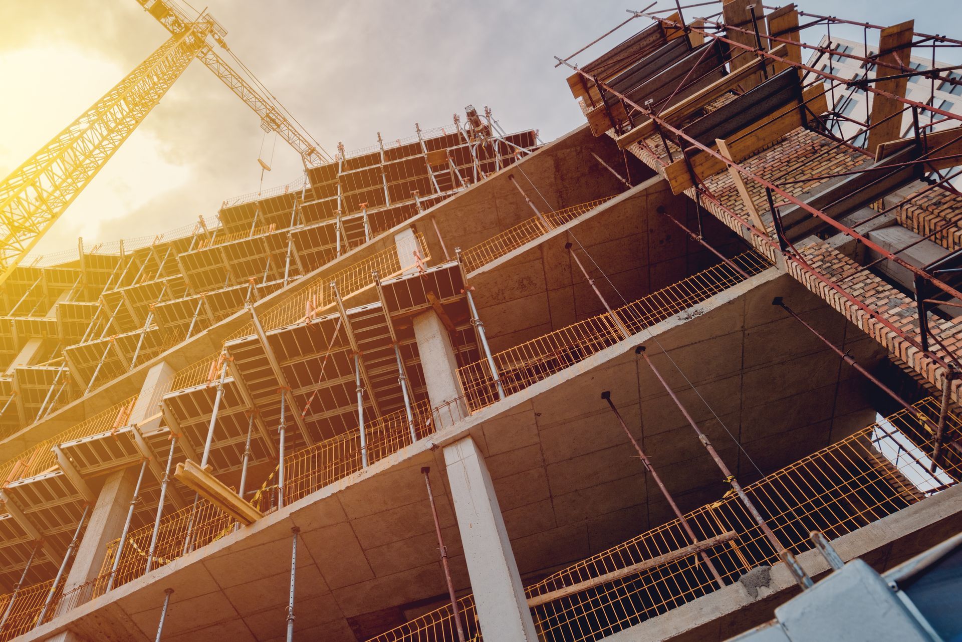 Construction site with scaffolding and a tall crane against a warm sky Construction site with scaffolding and a tall crane against a warm sky
