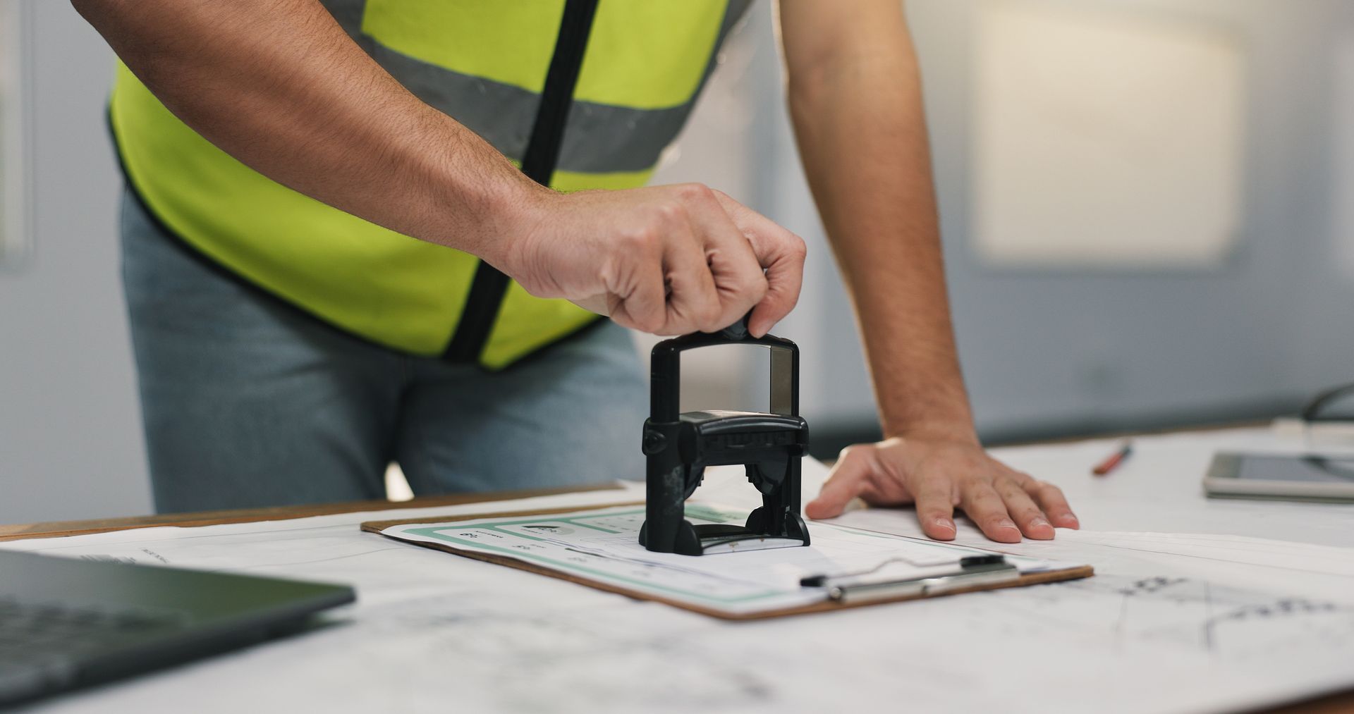 Worker stamping papers on a desk with a black seal in an office setting