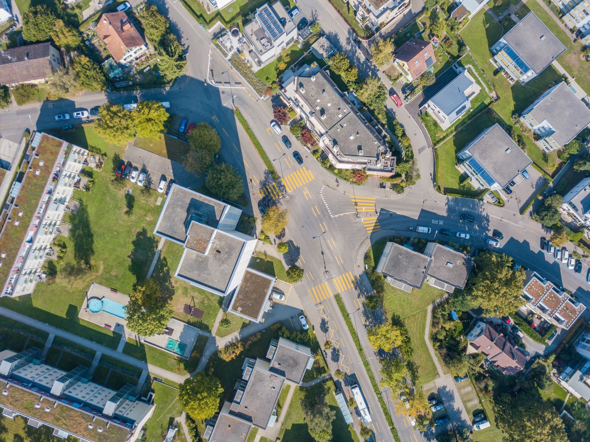 Aerial view of a suburban neighborhood with houses, streets, trees, and a small pool Aerial view of a suburban neighborhood with houses, streets, trees, and a small pool