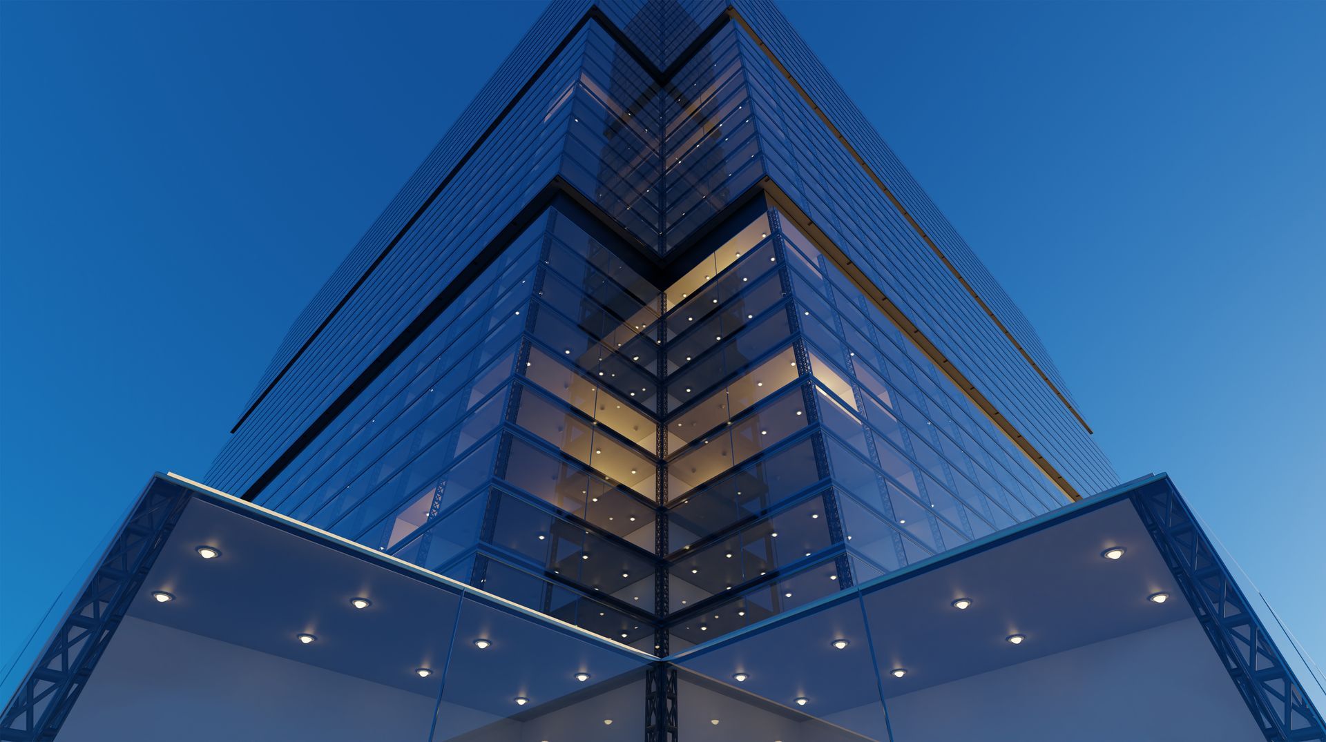 Modern glass skyscraper viewed from below at dusk, with blue sky and illuminated windows Modern glass skyscraper viewed from below at dusk, with blue sky and illuminated windows