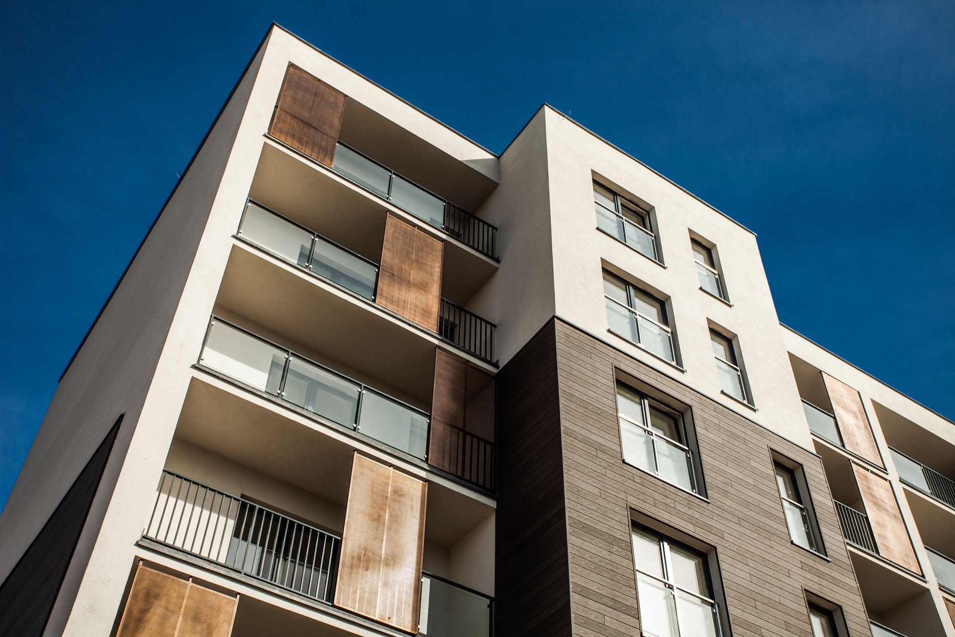 Low-angle view of a modern apartment building with balconies against a blue sky Low-angle view of a modern apartment building with balconies against a blue sky