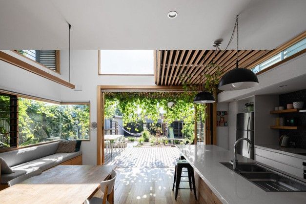 Modern open-plan living room and kitchen opening to a bright garden patio through large sliding glass doors Modern open-plan living room and kitchen opening to a bright garden patio through large sliding glass doors