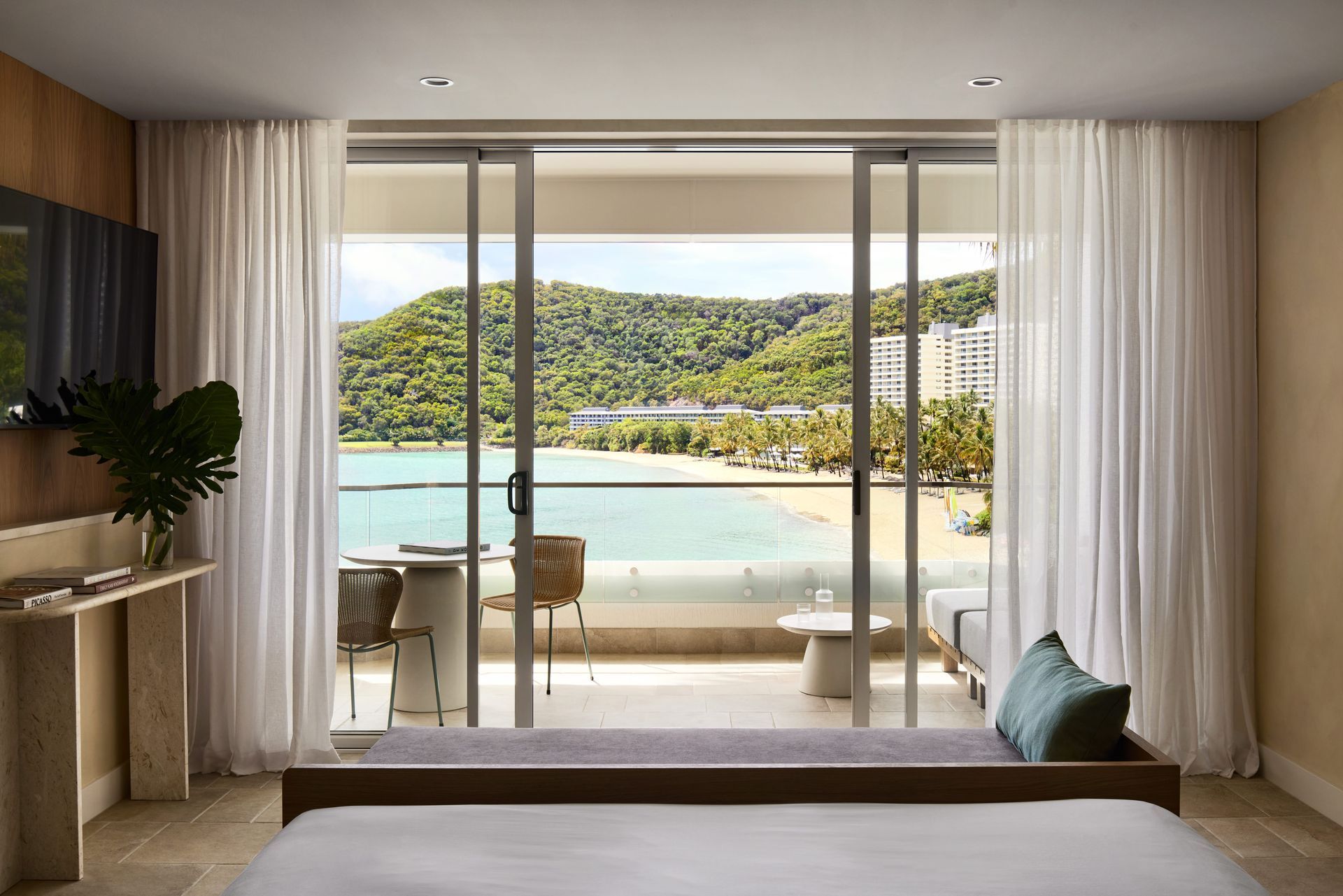 Bedroom with sliding glass doors opening to a balcony and tropical bay view