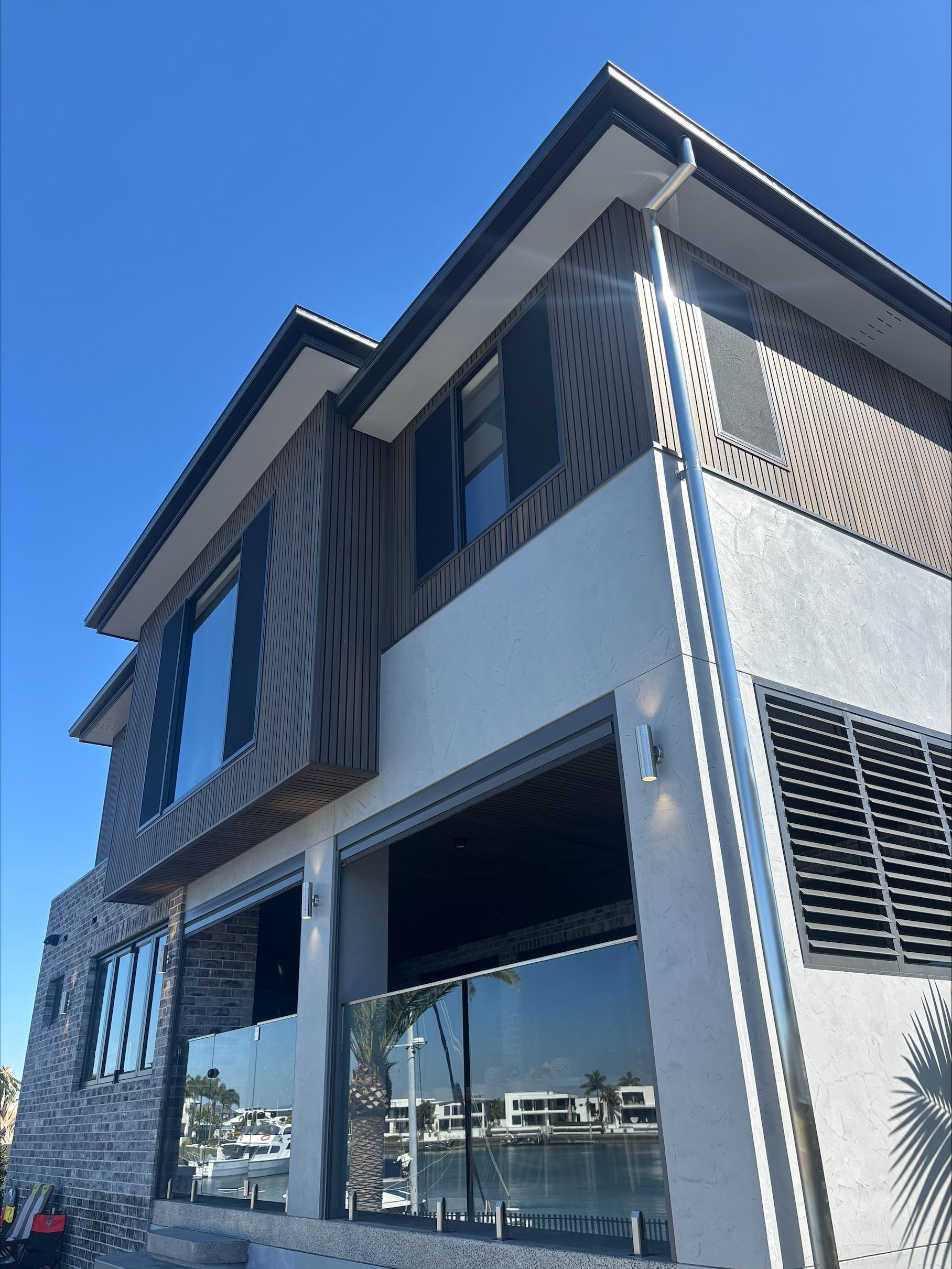 Modern two-story building with white walls, dark wood accents, and large windows under a blue sky