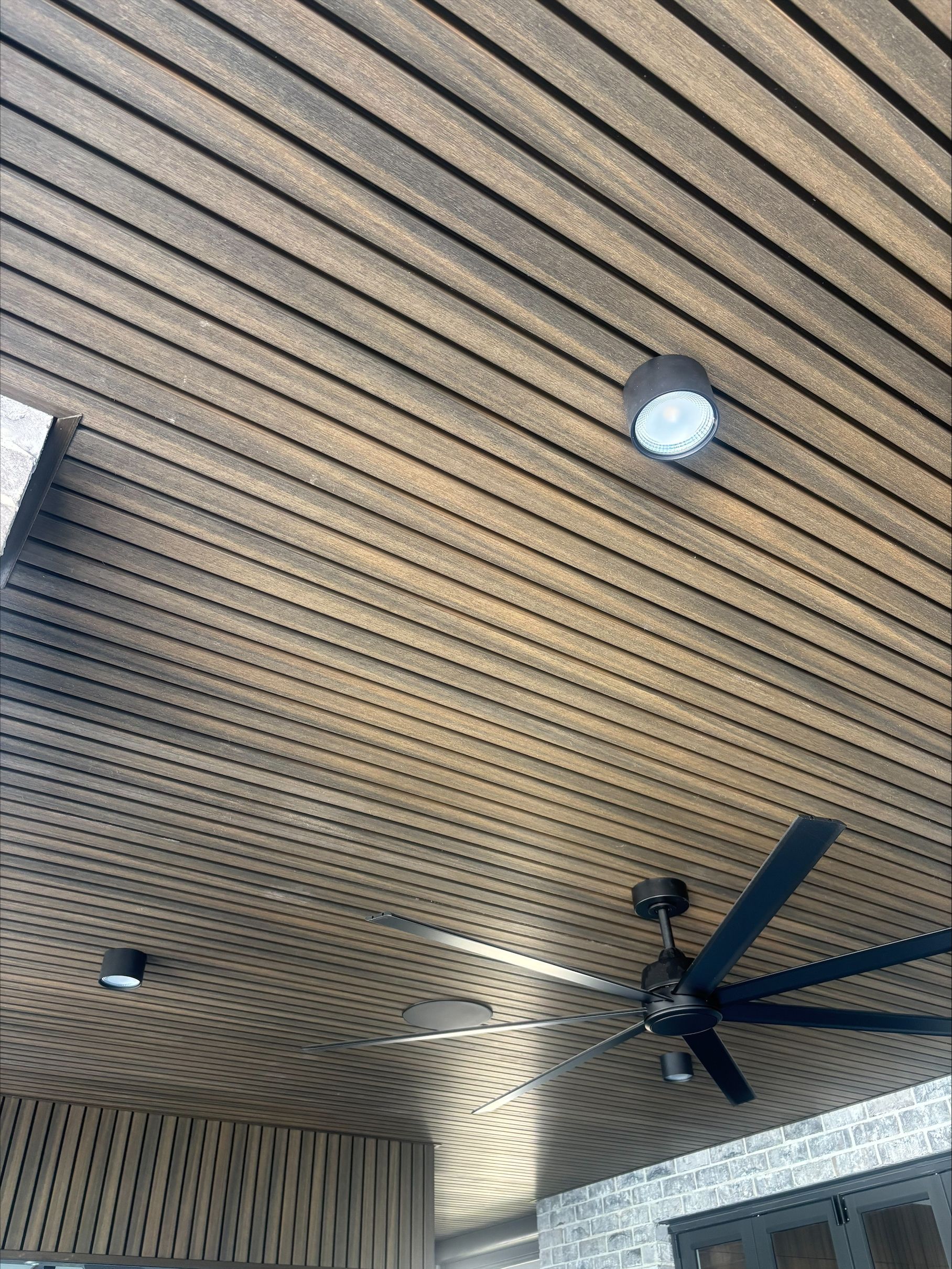 Covered patio ceiling with wood slats, recessed lights, and a ceiling fan