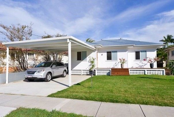 Single-story white house with a carport, parked silver SUV, and a green lawn on a sunny day