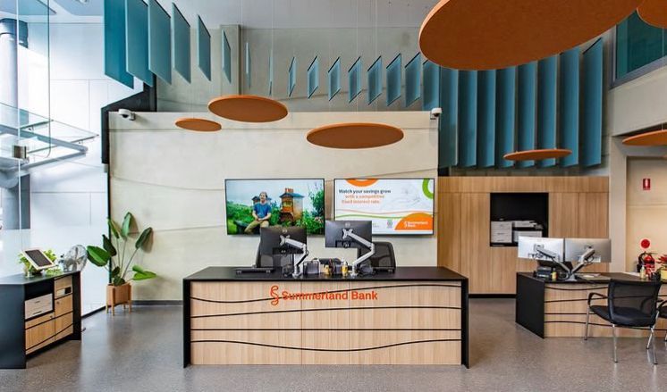 Modern office lobby with reception desk, plants, screens, and teal acoustic wall panels