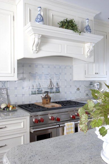 Bright white kitchen with a stainless range, decorative hood, tiled backsplash, and granite countertop