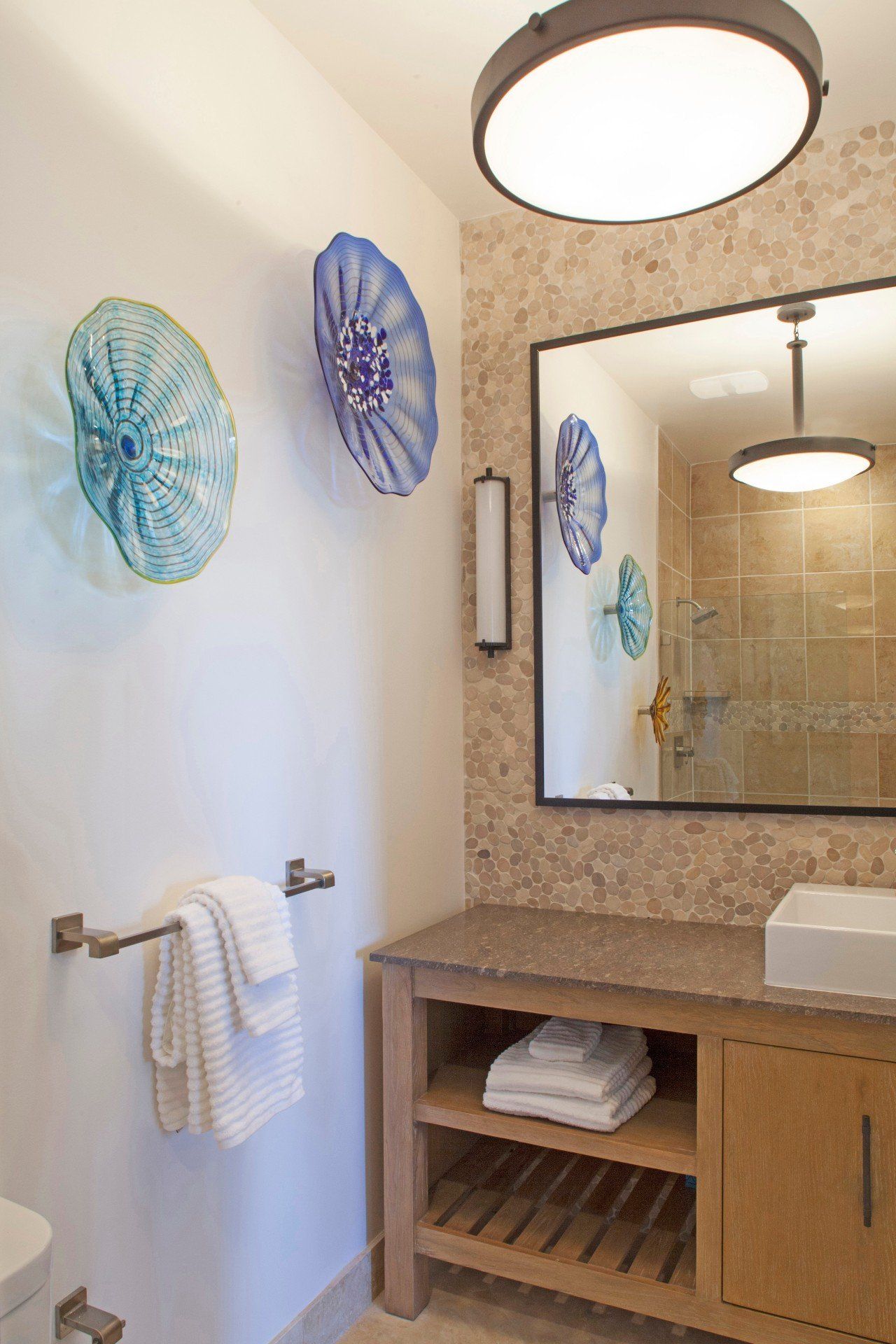 Modern bathroom vanity with large mirror, round lights, blue wall decor, and towel bar