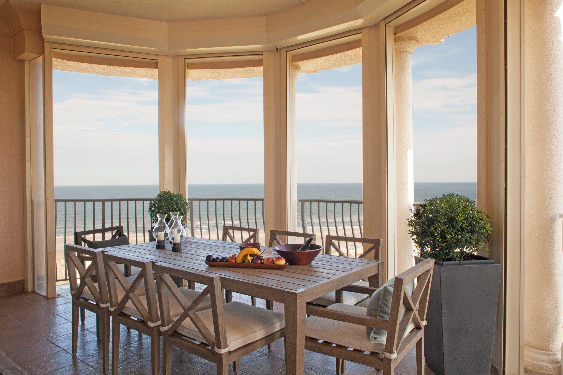 Dining table on a seaside balcony with ocean view through large windows