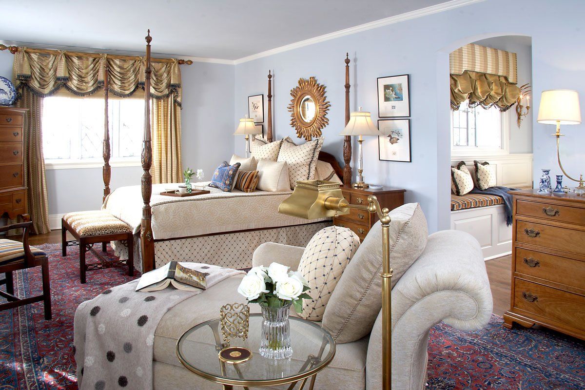 Elegant blue-and-cream bedroom with upholstered chair, dresser, bed, and patterned curtains