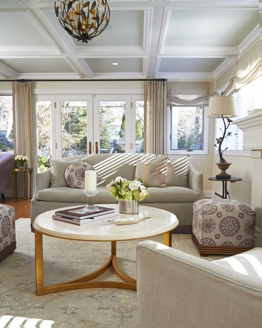 Bright living room with cream sofa, marble coffee table, and large windows under a coffered ceiling