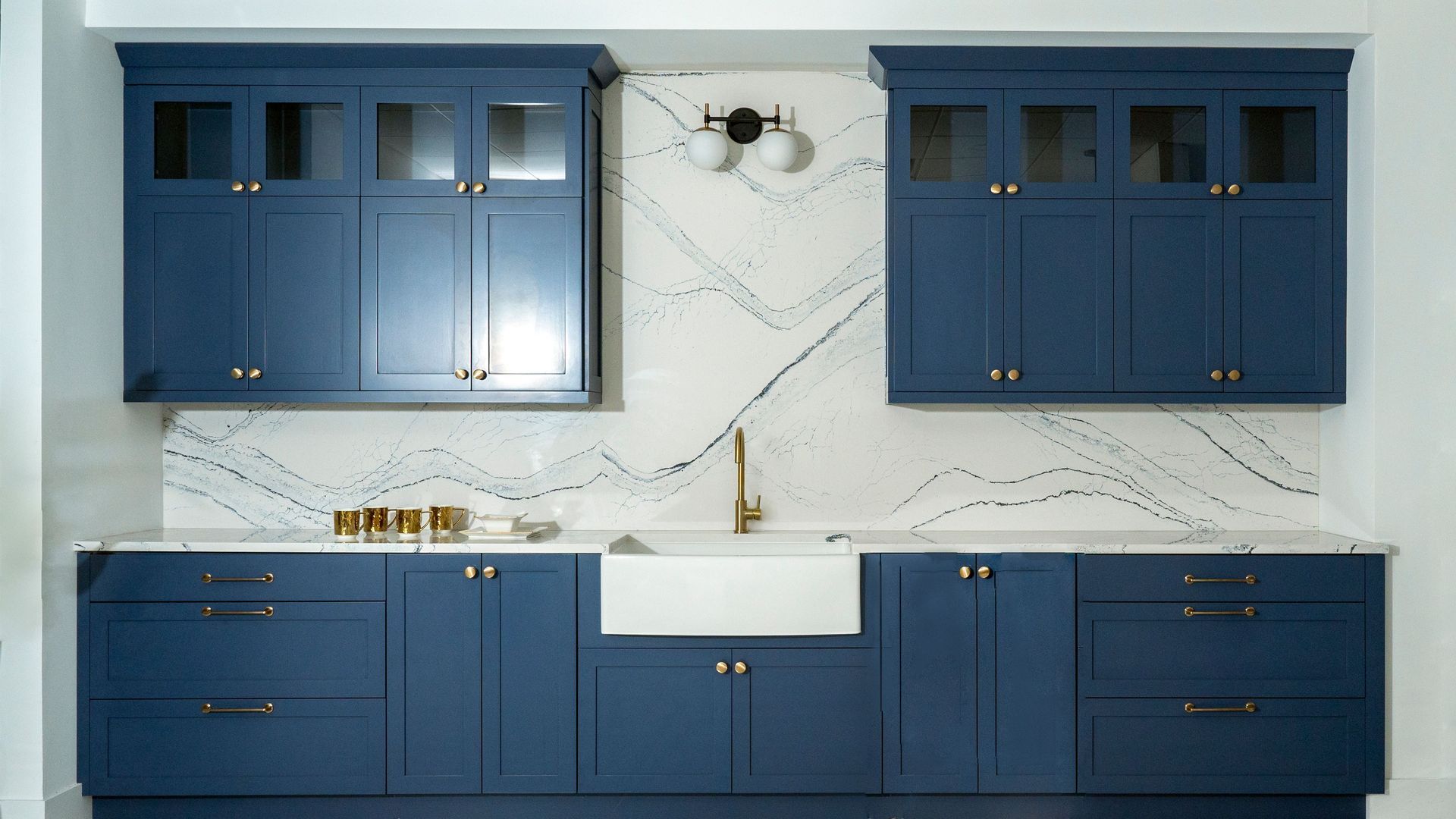 Blue kitchen cabinets with white marble backsplash and central sink counter