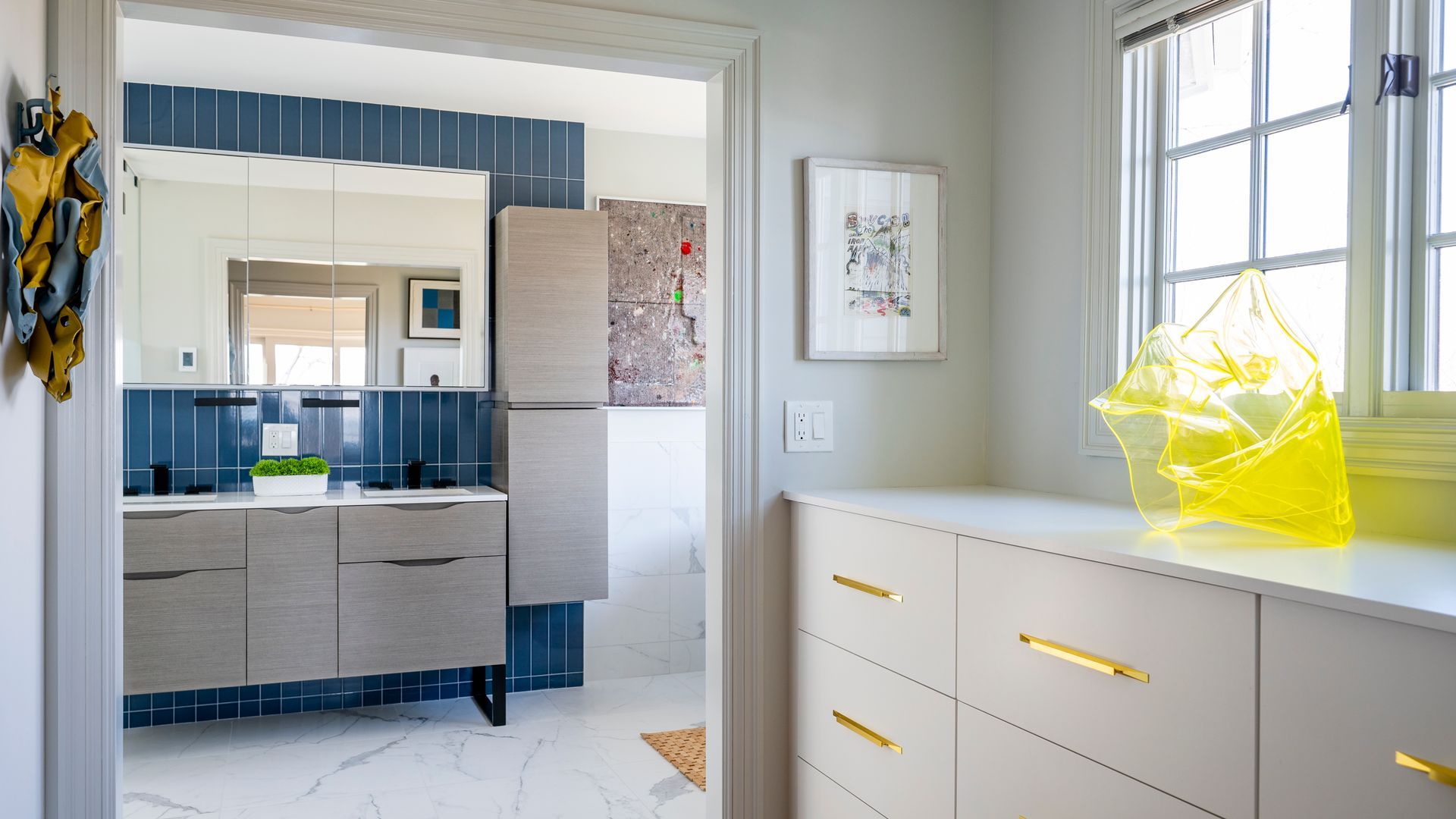 Bright bathroom with white vanity, blue accent wall, and yellow tissue box by a window