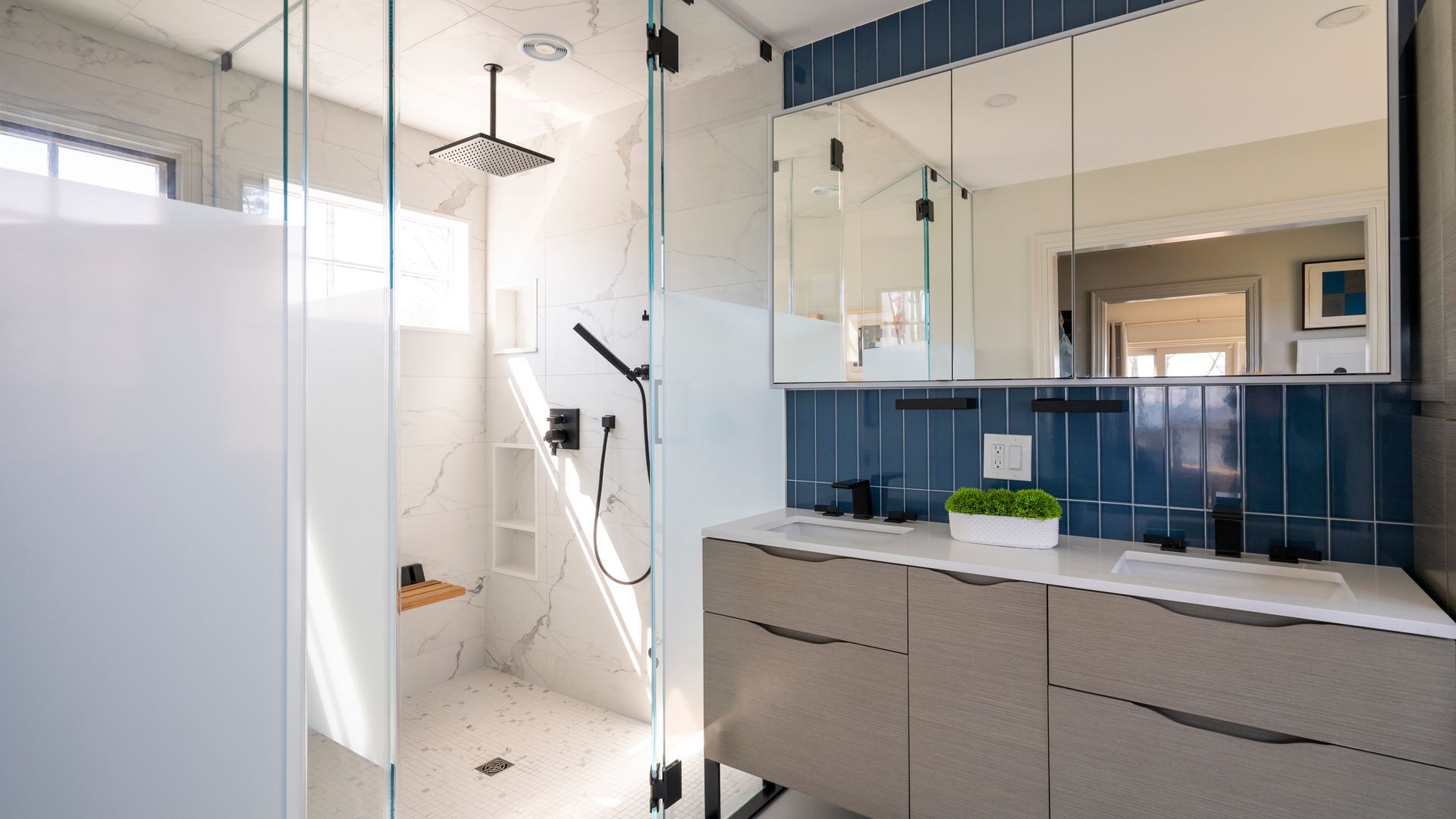 Modern bathroom with glass shower, blue tile wall, and double sink vanity