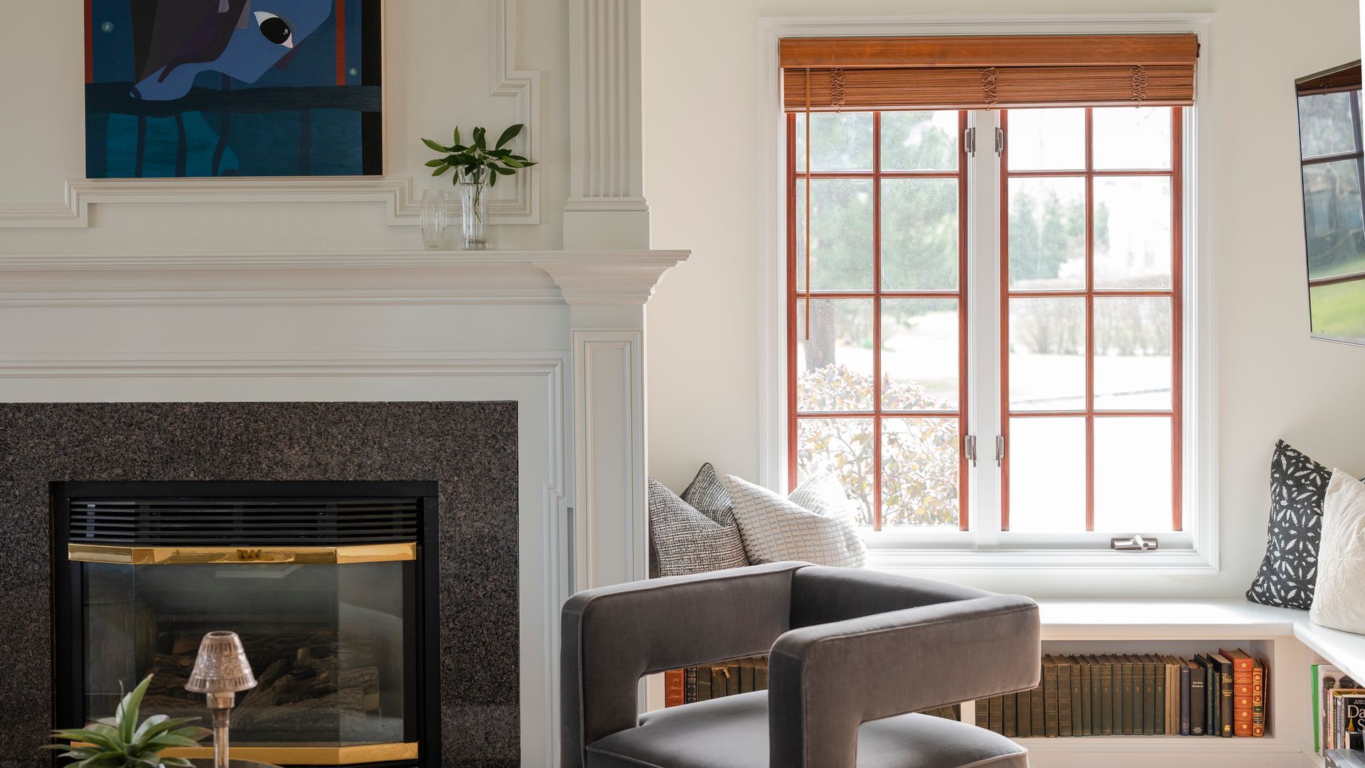 Bright living room with fireplace, white mantel, bay window, and gray seating nook