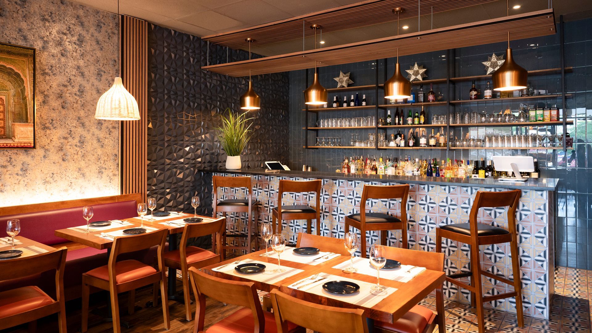 Warm, modern restaurant interior with wooden tables, bar seating, hanging lights, and brick walls.