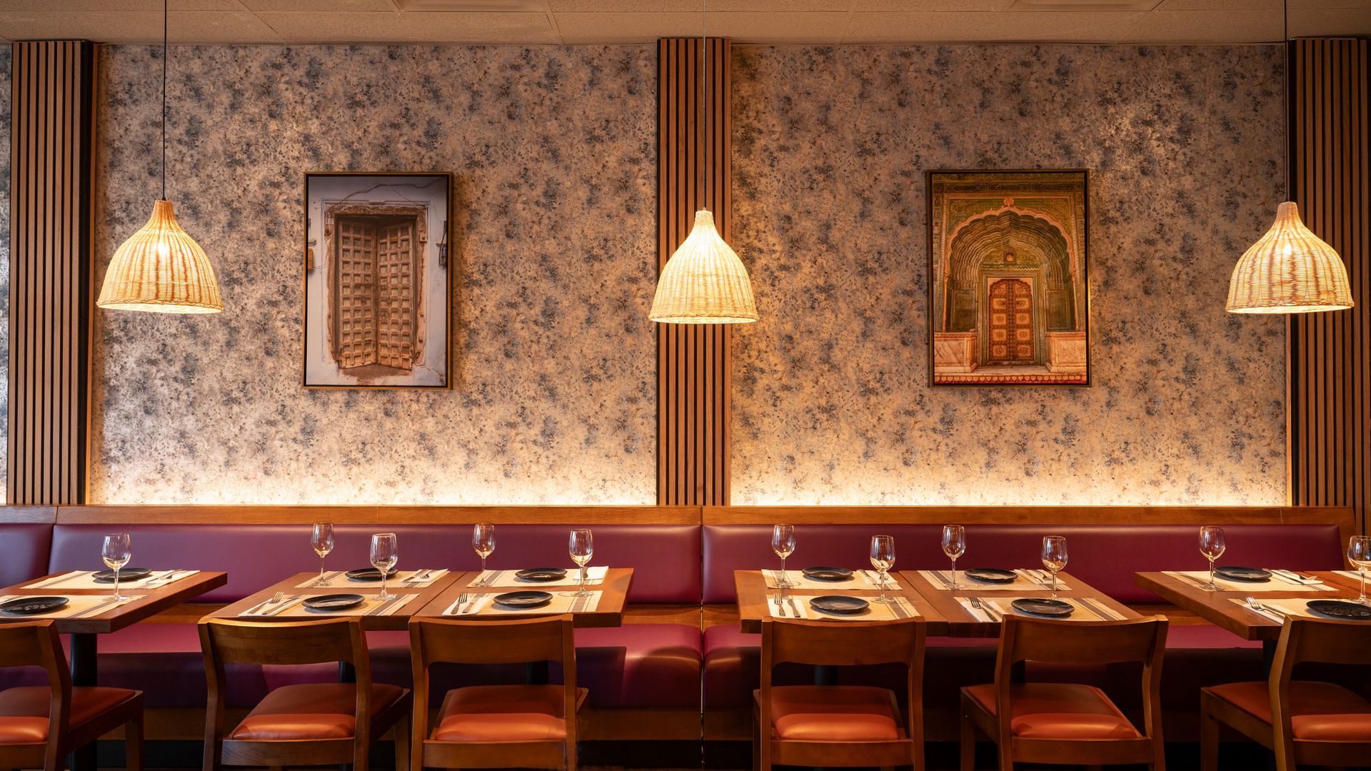 Cozy restaurant dining room with patterned wallpaper, pendant lights, framed art, and neatly set tables and chairs