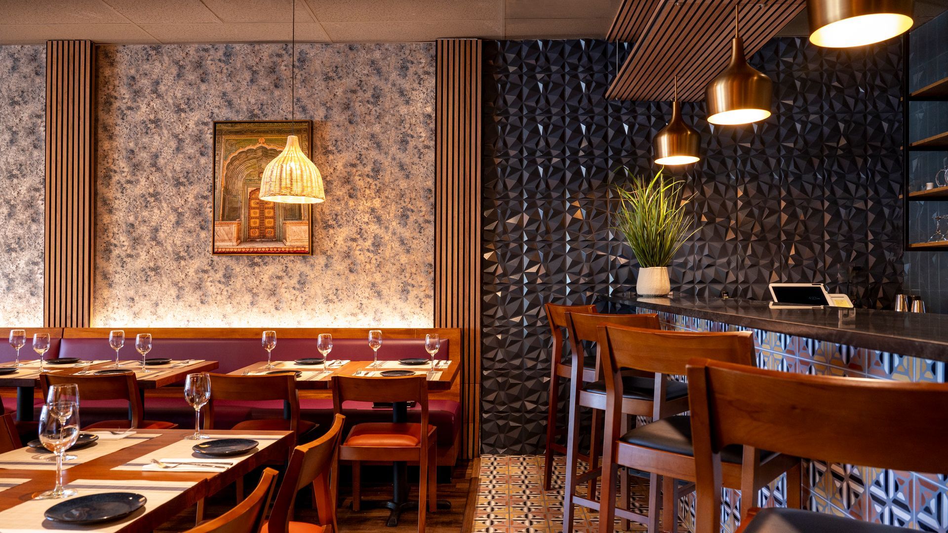 Cozy restaurant interior with wooden tables, red booths, pendant lights, and patterned wallpaper