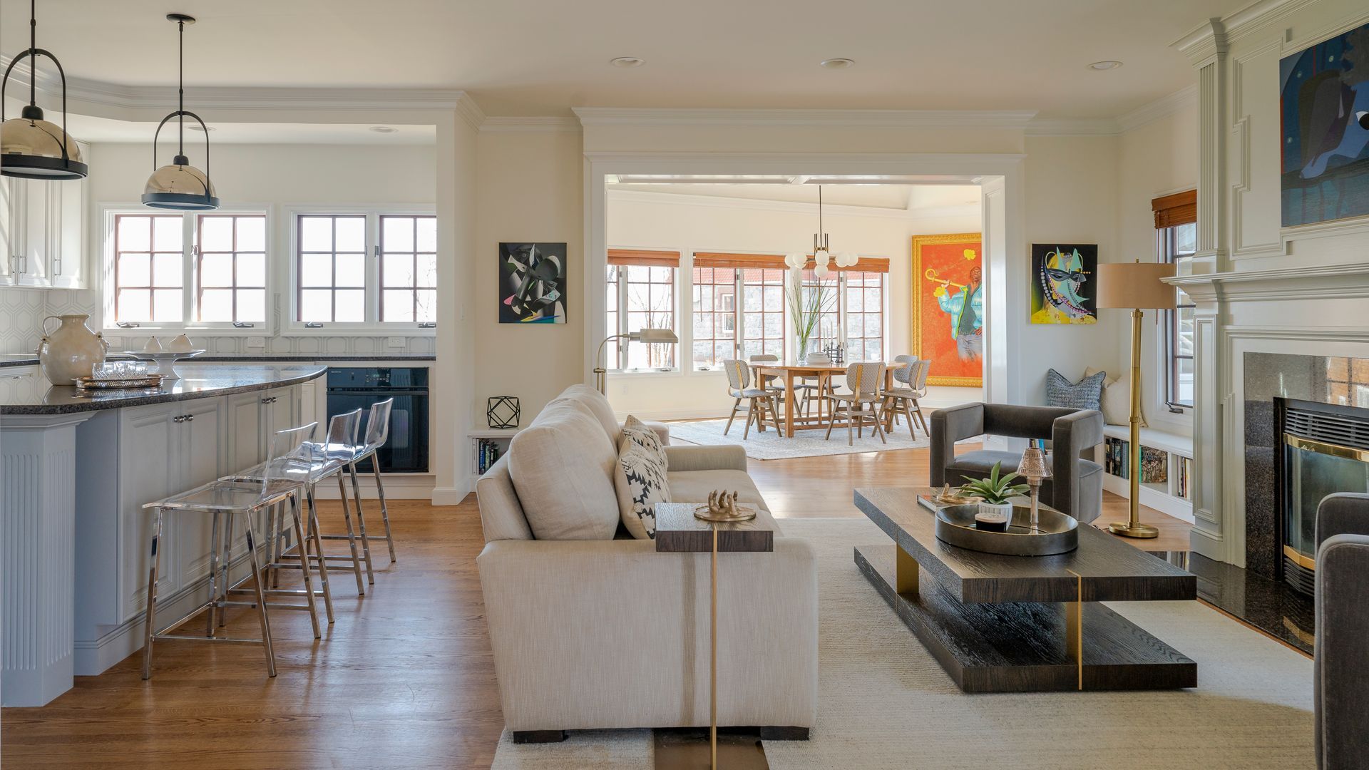 Bright open-plan living room with beige sofa, fireplace, kitchen island, and dining area in the background.