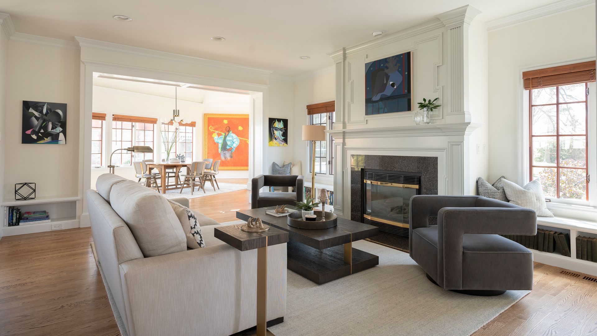 Bright living room with beige sofas, a fireplace, and a dining area visible through wide openings.