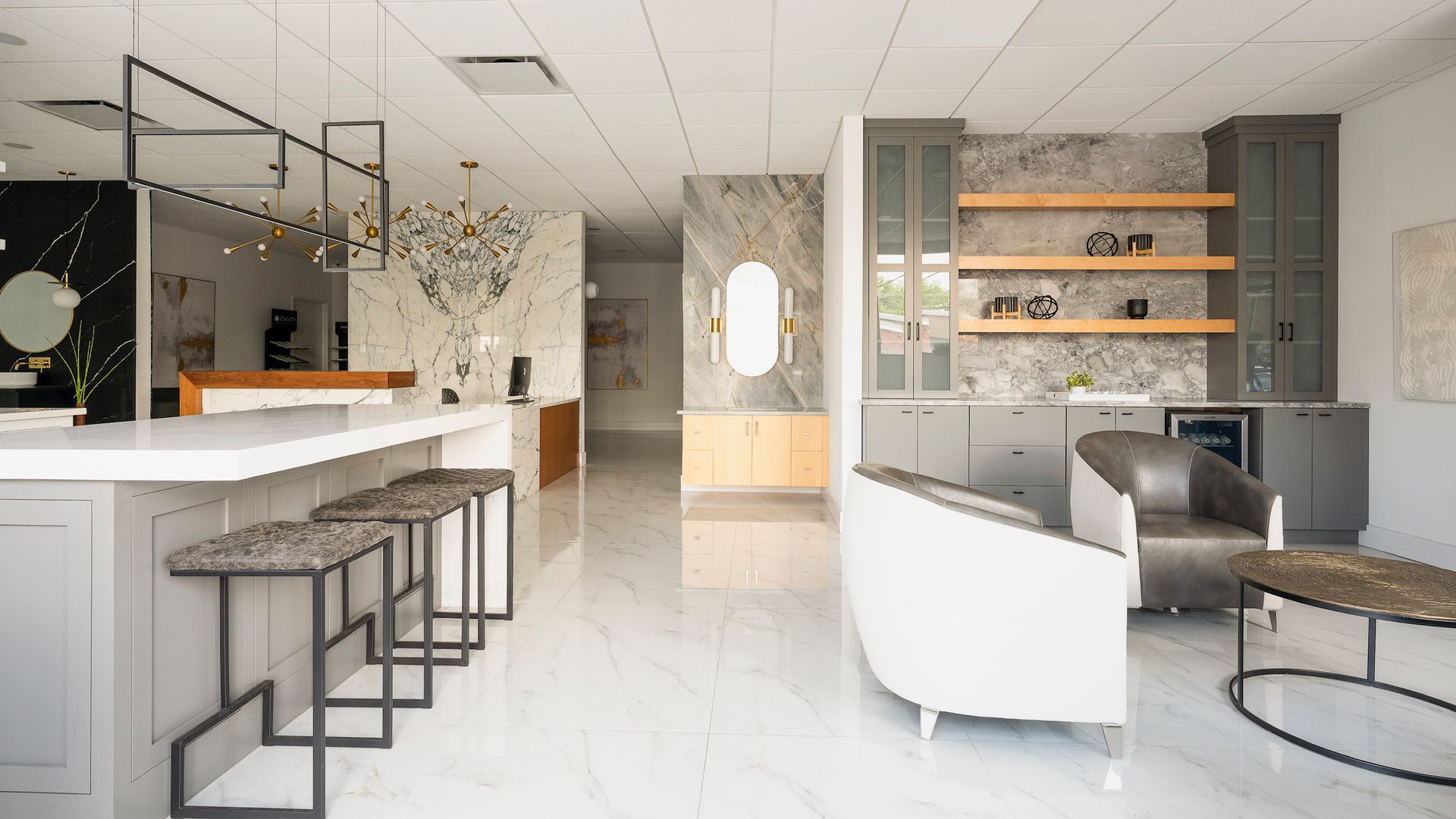 Modern open-plan lounge with white seating, bar stools, and wood shelves in a bright, minimalist interior