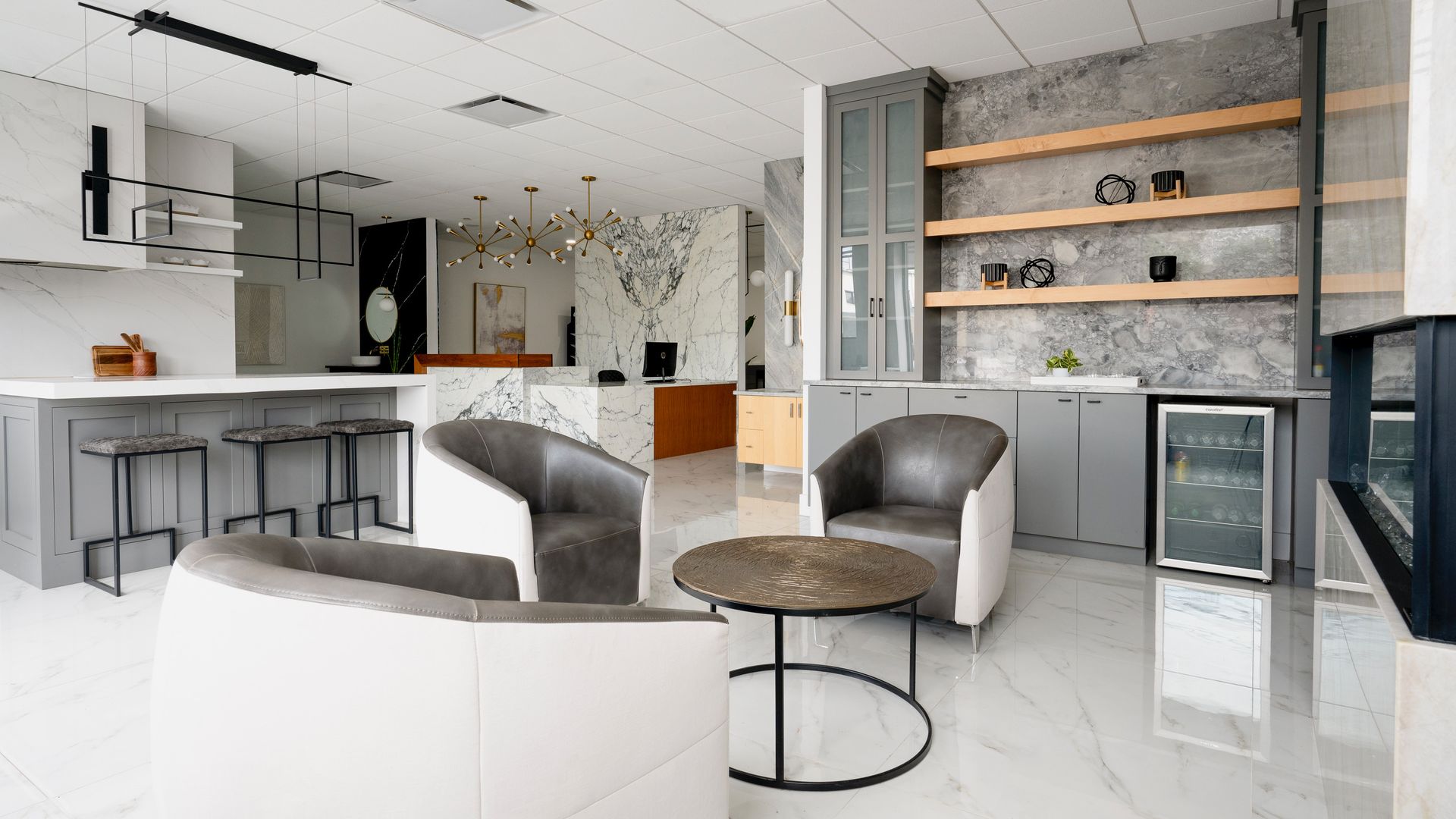 Modern office lounge with curved white seating, gray chairs, wood shelving, and a small round table