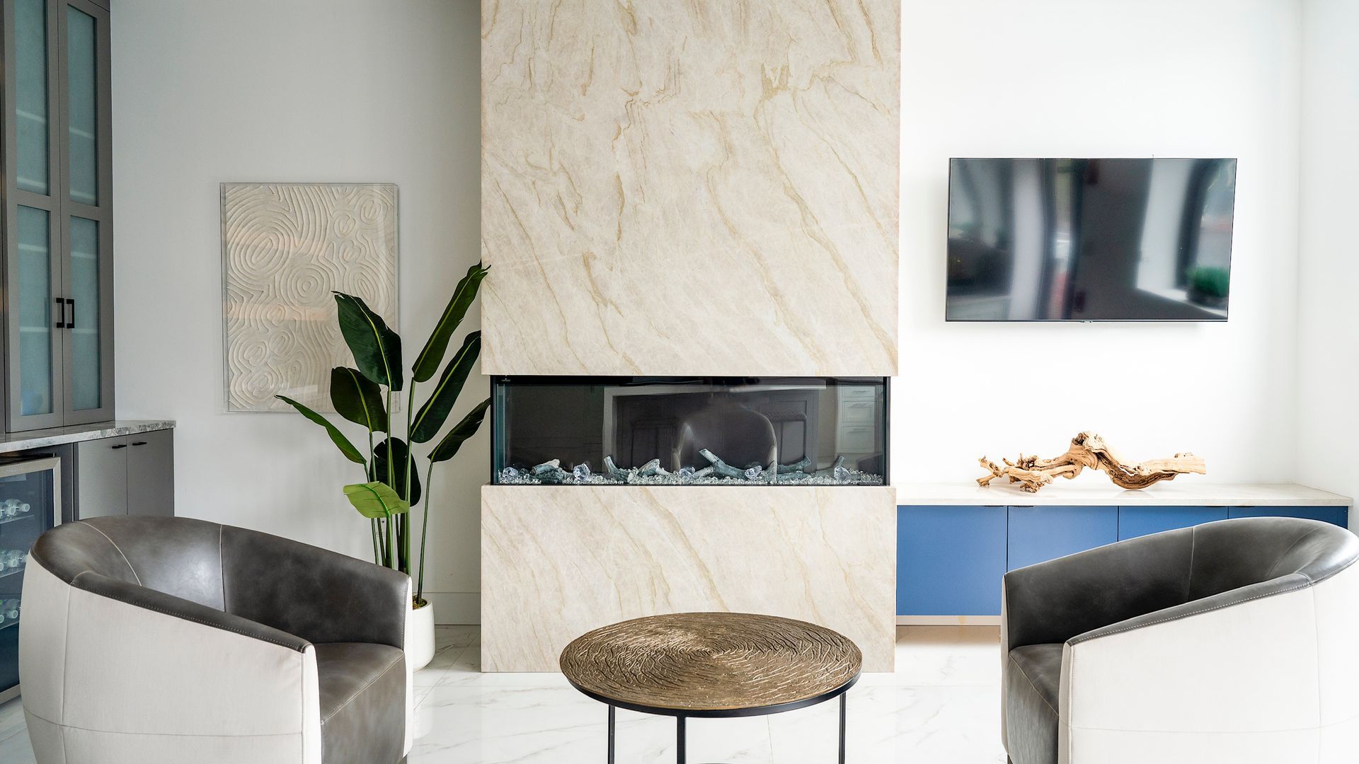 Modern living room with fireplace, wall-mounted TV, round coffee table, and two white chairs