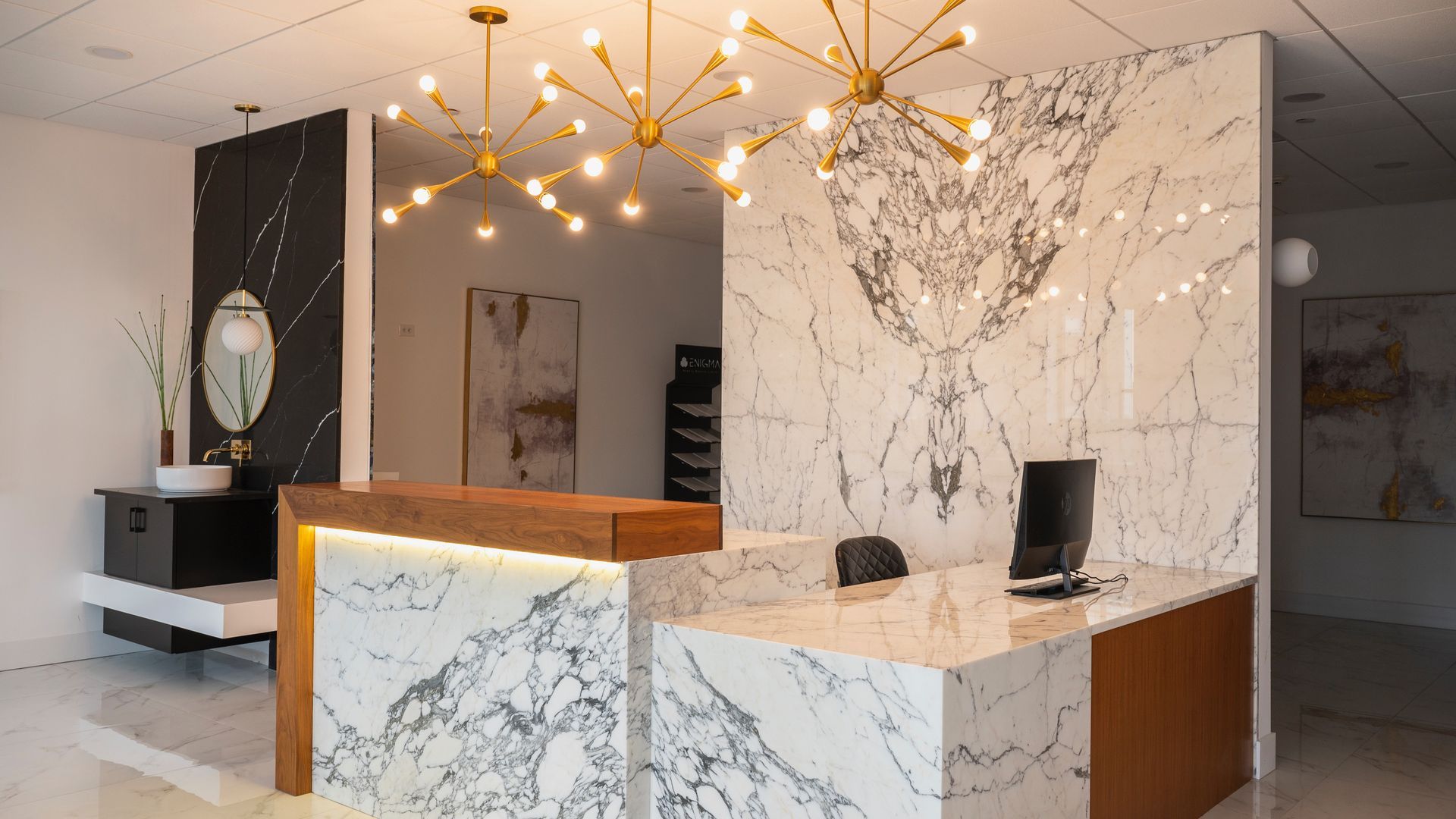Modern marble reception desk in a stylish lobby with gold chandeliers and white walls