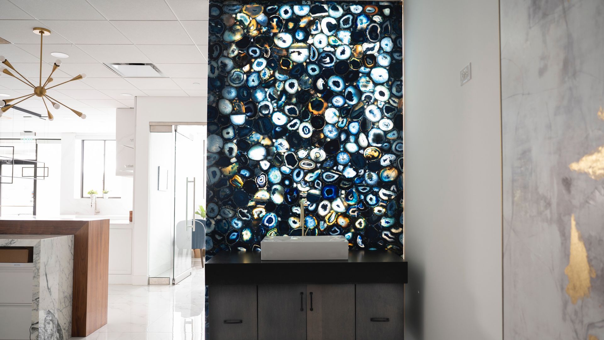 Modern interior with a large abstract blue-and-white artwork above a dark cabinet in a bright room