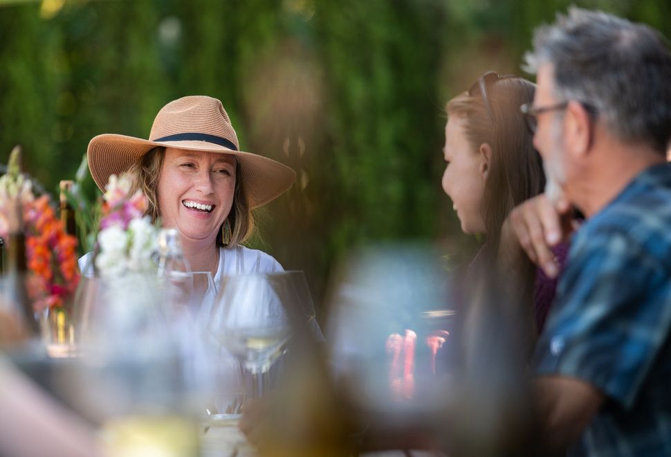 Guests in sun hats laughing together at an outdoor Brashley dinner