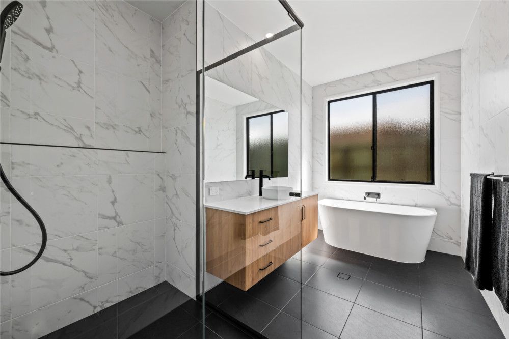 A Bathroom with A Bathtub , Sink , Shower and Mirror — Peter Betros Homes in Highfields, QLD