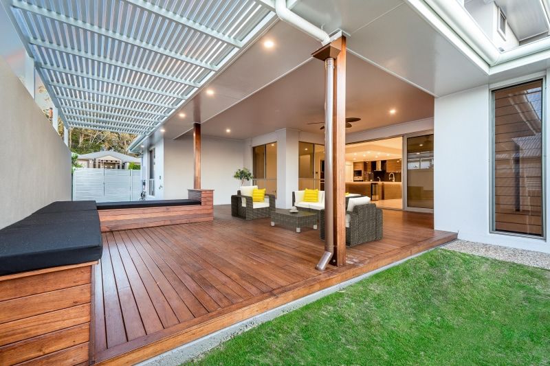 A Patio with A Wooden Deck and Chairs Under a Pergola — Peter Betros Homes in Highfields, QLD