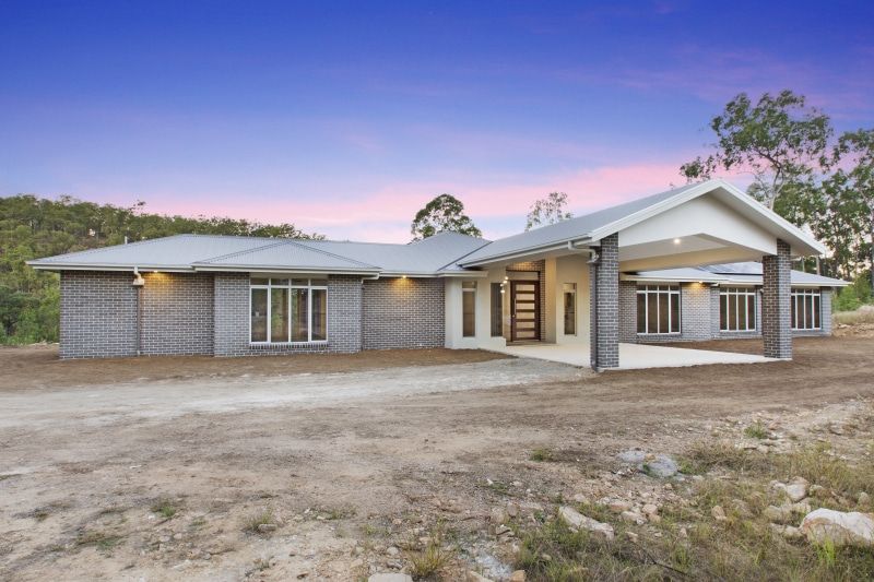 A large house is sitting in the middle of a dirt field — Peter Betros Homes in Highfields, QLD